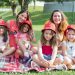 Friends enjoying a sunny day picnic on grass with bucket hats and smiles in a Portuguese park.