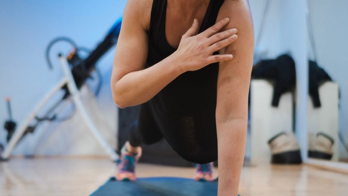 A woman in a black tank top is doing yoga